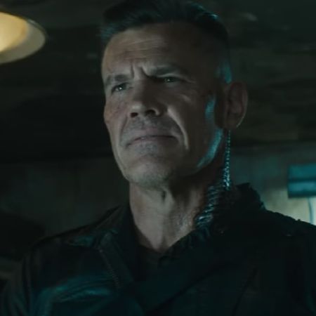 Josh Brolin is in a black soldier outfit in a dark lit room.